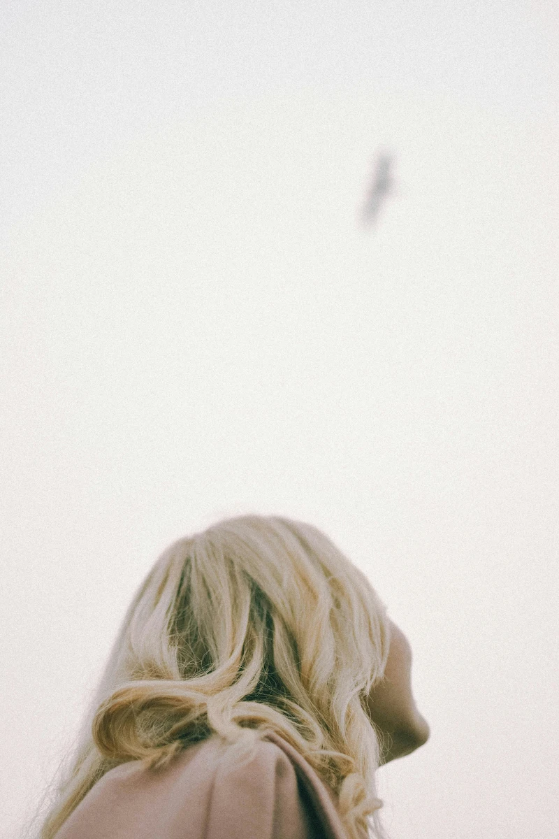 woman watching a bird soaring high in the sky